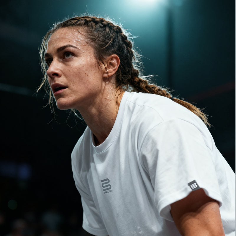 Woman in a white sports outfit with braided hair on a dark background